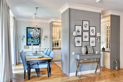 Upholstered chairs around dining table next to open-plan kitchen in elegant apartment