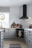 Grey base units and extractor hood in kitchen with white subway tiles