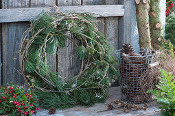 Wreath made of pine branches and clematis tendrils, basket with pinecones