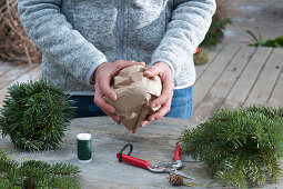 Christmas tree ornaments in forest motif: Woman shapes paper ball to wrap around