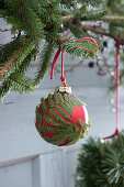 Christmas tree baubles in forest style: red Christmas tree baubles with fern leaves glued to a spruce branch