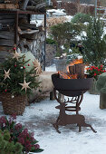 Snowy, Christmassy terrace with fire bowl and Christmas tree, silhouette of a deer made of stainless steel