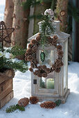 Lantern with a wreath of larch cones, fir branch, and Christmas tree decorations