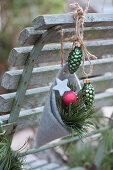 Selbstgemachte Filztüte mit Christbaumschmuck und Kiefernzweig an Stuhllehne gehängt