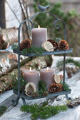 Metal étagère with candles, cones, fir branches, and Christmas tree decorations on a table