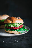 Vegetarian bagel burger with red beet patty and avocado