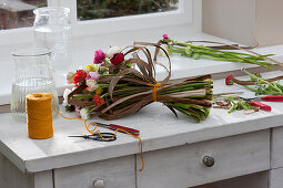 Unusual spring bouquet of ranunculus and dried stalks of Chinese reed lies on the work table