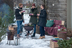 Friends standing comfortably around the barbecue drinking hot punch, pots of punch on the barbecue