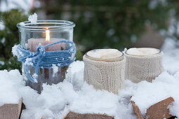 A Lantern with wool yarn in the snow, cups with hot chocolate and frothed milk