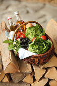 A basket of lettuce, tomatoes, eggs, olives, oil and vinegar
