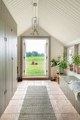 Hallway with floor-to-ceiling built-in cupboards and bench, open French doors leading to garden