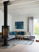 Fireplace and corner sofa in living room with white-painted wood cladding