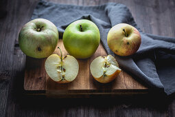 Äpfel, ganz und aufgeschnitten auf Holzbrett
