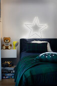 Bed with dark bedding, star shining above it in the children's room