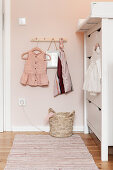 Babykleidchen auf Garderobenleiste neben Wickelkommode