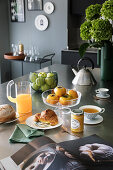 Laid breakfast table with croissant, jam, tea, fruit, and juice