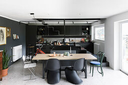 Dining area in front of a black fitted kitchen cabinets with a kitchen island, stairs to the gallery