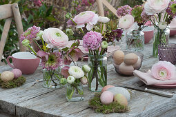 Easter table decoration with ranunculus and spring roses, Easter eggs on moss