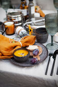 Autumn table with pumpkin soup and plums