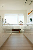 Kitchen with white, high-gloss cabinets and view of bench with cushions