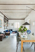 Pendant lamp above dining table with modern chairs, seating area in background