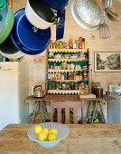 Pans hanging over kitchen table with shelved in background