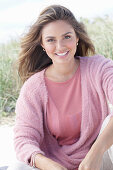 A young, long-haired woman wearing a pink blouse and a pink wrap-around jumper