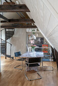 Marble table and cantilever chair in attic room with spiral staircase in the background