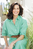 An older brunette woman wearing a green dress