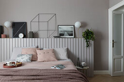 Doppelbett vor Holzvertäfelung mit Dekoobjekten im Schlafzimmer