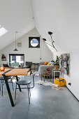 Dining table with chairs, in the background seating area in the loft