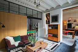 Sofas and coffee table in front of wooden wall and retro bureau in loft apartment