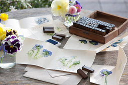 Designing greeting cards card with Imprinted pressed flowers, with a box filled with stamp letters