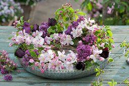 Wreath of crab apple branches, lilacs and black tulips in a silver bowl