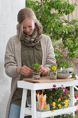 Easter terrace: woman decorates small glasses with parsley