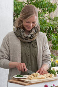 Osterterrasse: Frau schneidet Lachsröllchen fürs Osterfrühstück