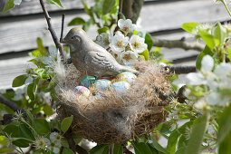 Easter nest with bird figurine and chocolate eggs in pear tree