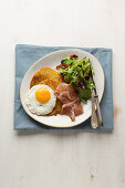 Potato pancakes with a fried egg and prosciutto