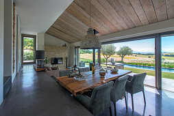 Dining area with wooden table top and elegant upholstered chairs next to sliding glass door and terrace