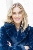 A young blonde woman wearing a blue faux fur coat