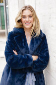 A young blonde woman wearing a blue faux fur coat