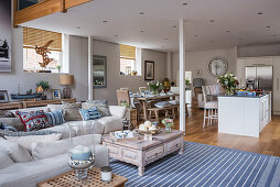 Offener Wohnraum im maritimen Stil mit Kücheninsel, Esstisch und Sofa