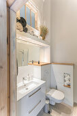 Blick auf Waschbecken mit Unterschrank und Toilette in hohem Badezimmer
