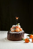 Schokoladen-Dripping-Cake mit Mandarinen und Wunderkerze