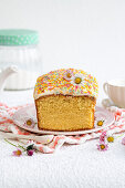 Vanilla cake with sugar icing and colourful sugar sprinkles, cut into pieces