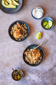 Reis mit Hähnchenoberkeulen (One Pot) serviert mit Chilis, Avocado und Limetten