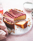 Rhubarb and Almond Cake with One Slice Resting on a Marble Board