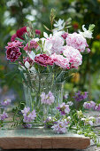 Small bouquet of carnation blossoms and magnificent candle, tendrils of crown vetch in front of it