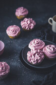 Cupcakes with pink frosting on a dark surface