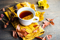 Eine Tasse Tee mit Zitrone drumherum Herbstlaub